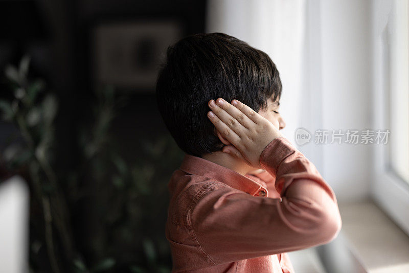 伤心的孩子在父母吵架时用手捂住耳朵。