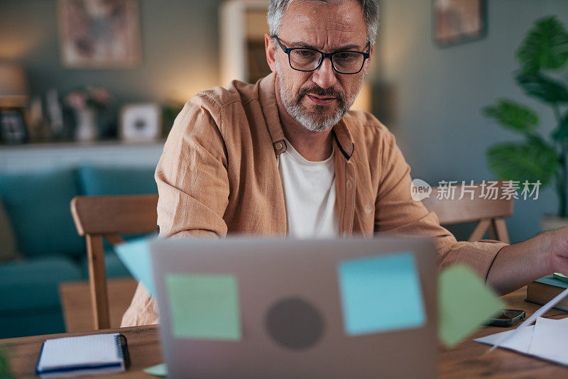 一个成年男子在家里用笔记本电脑上网的照片