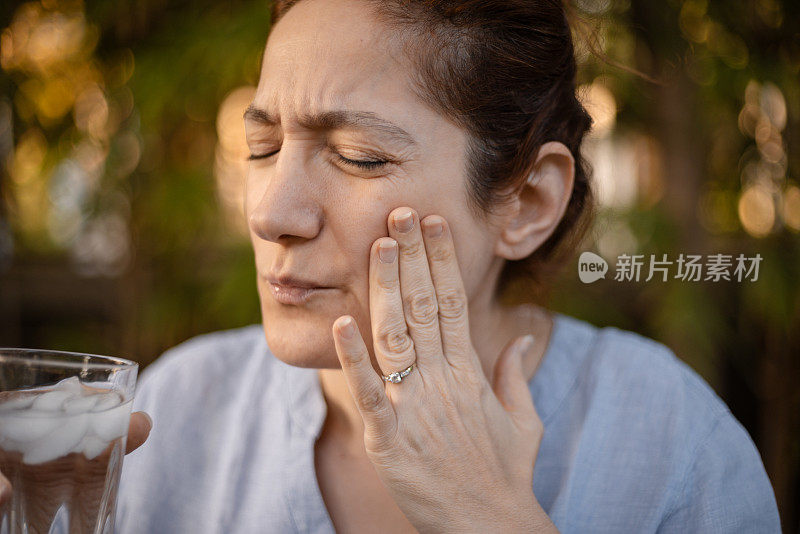 一名白人妇女在喝了一口冰水后出现牙齿疼痛的反应，这是敏感牙齿系列的一部分