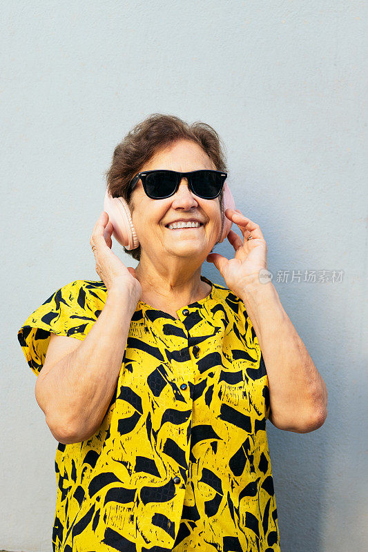戴着墨镜，戴着耳机听音乐的时髦老妇人