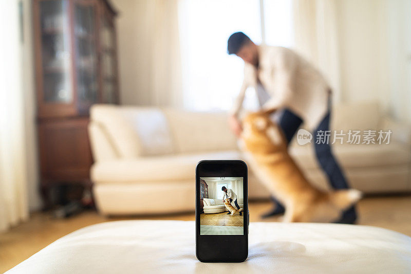 男子一边和狗跳舞一边用手机拍照