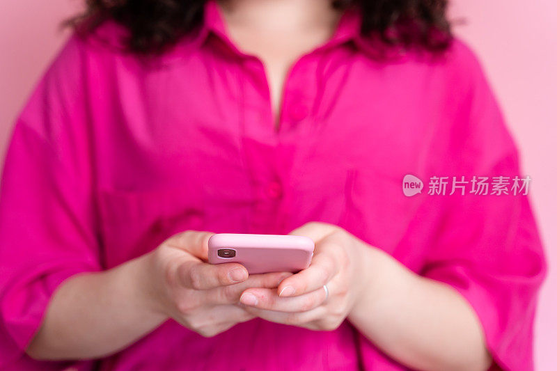 穿粉色衬衫的女人用智能手机发短信