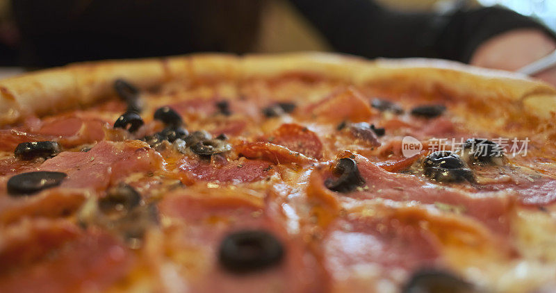 旋转新鲜披萨，侧视图，特写。香肠，橄榄，培根。肉意大利新鲜披萨。
