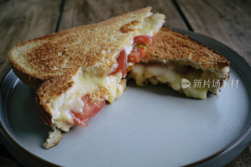 灰色盘子里的奶酪和西红柿烤三明治特写。