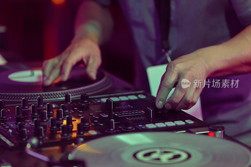 嘻哈DJ在唱盘上刮黑胶唱片。唱片骑师的手抓挠唱片在转盘播放器在近距离