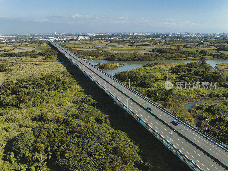 汽车在高速公路路口行驶的鸟瞰图。桥梁道路与绿色花园和树木相连接的建筑概念。