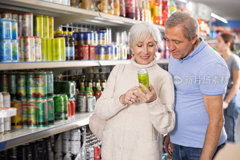 老年夫妇在超市的食品杂货区一起挑选铝罐碳酸饮料