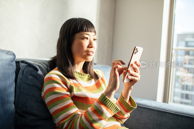 年轻的日本女性在家里使用智能手机