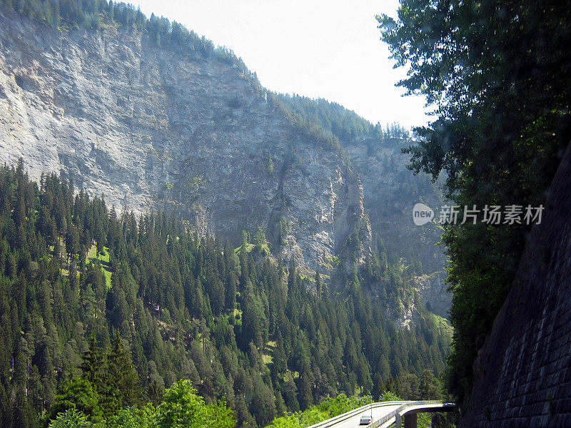 高耸的石崖上的山桥和一辆汽车行驶在它上面。如画的夏日风景