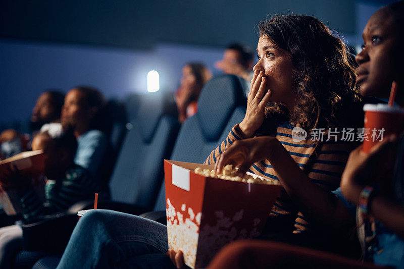 震惊的女人在电影院看悬疑电影。