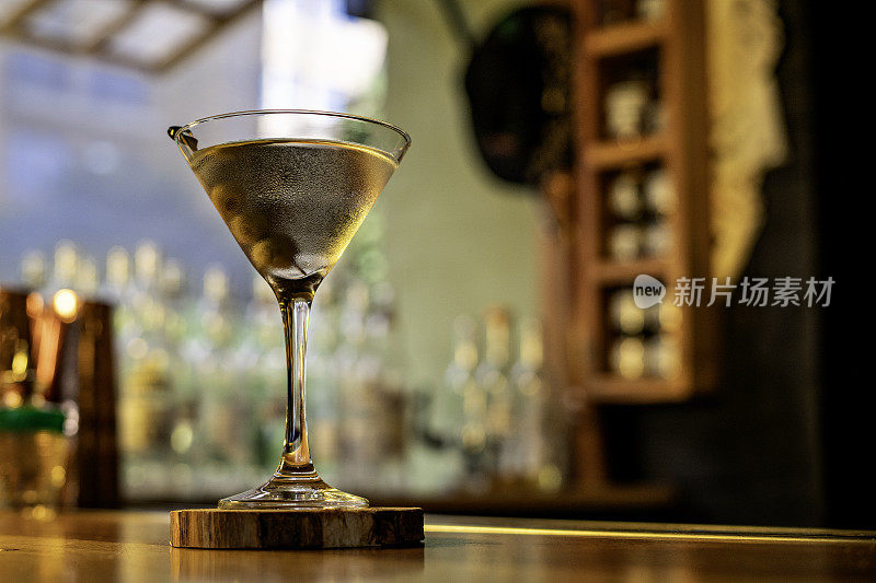 经典的干马提尼鸡尾酒与橄榄在模糊的背景酒吧。