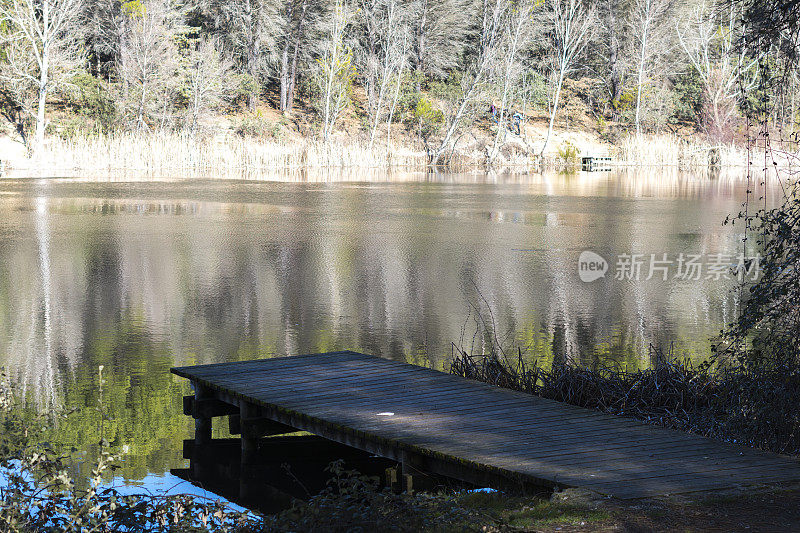 孤独的木制防波堤延伸到平静的湖面上——西班牙湖