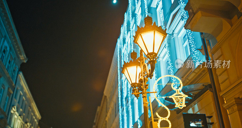 在匈牙利布达佩斯，圣诞灯柱和建筑物在夜空下的低角度视角