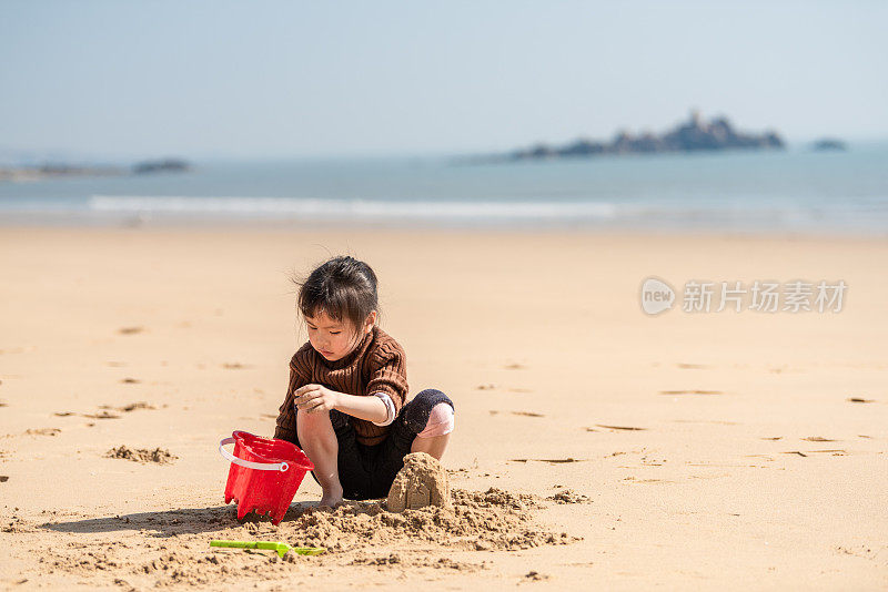 一个中国小女孩在沙滩上玩沙子