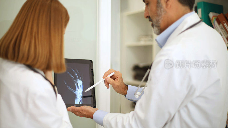 医疗专业人员正在讨论电子平板电脑上的x光图像。