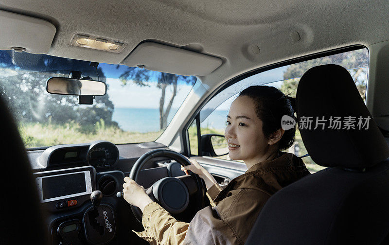 海边之旅:微笑的亚洲女人在方向盘上