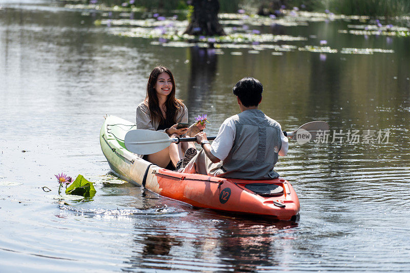 亚洲迷人浪漫的年轻夫妇划船在森林湖。背包客男女旅行和皮划艇在美丽的红树林享受一起度过假期的时间。