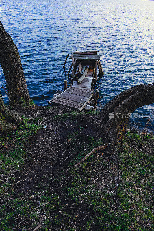 秋景——湖水和毁坏的木码头。秋天，森林里的湖上，老旧的烂木码头，缺了木板，有长凳。