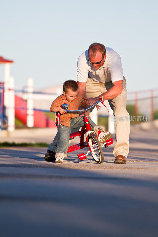 爸爸和小男孩骑三轮车