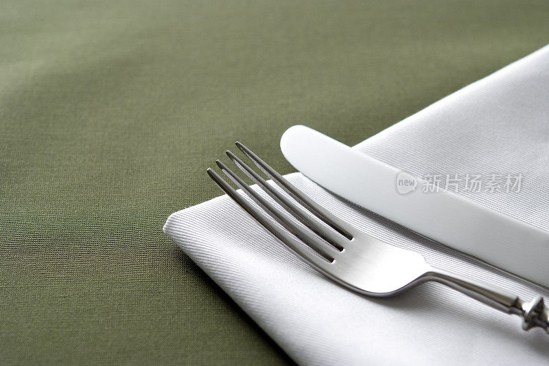 刀叉，白色餐巾，绿色桌布