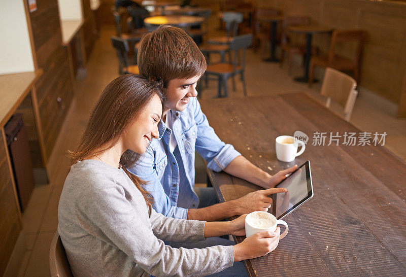 一对深情的年轻夫妇在咖啡店里使用数码平板电脑