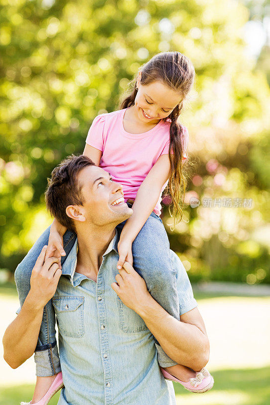 在公园里，父亲用肩膀扛着女儿