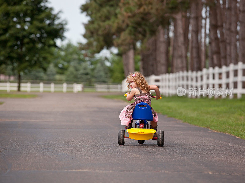 在牧场上骑三轮车的小女孩