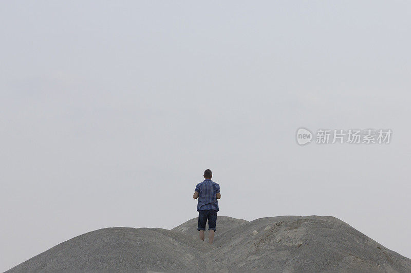 一个人站在沙砾沙丘的顶端