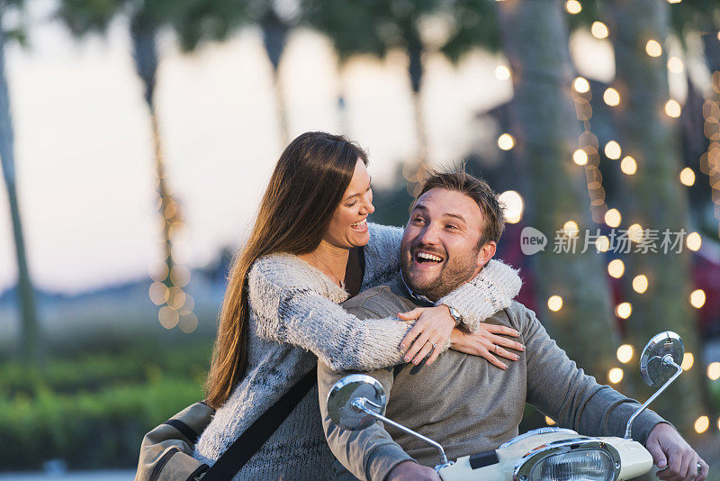 幸福的年轻夫妇，女人在摩托车上拥抱男人