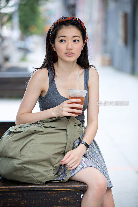 年轻女子在街上喝冰茶
