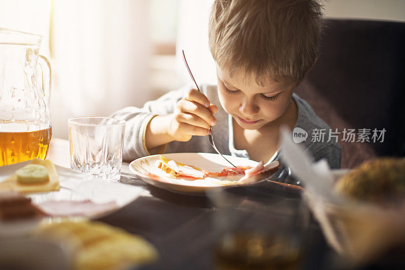 小男孩在阳光明媚的早晨吃早餐