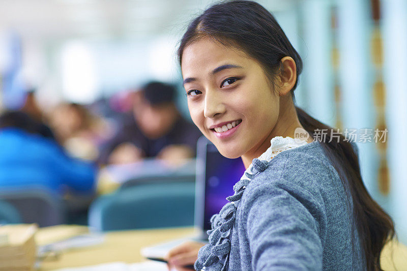 一个年轻漂亮的亚洲大学生在图书馆学习