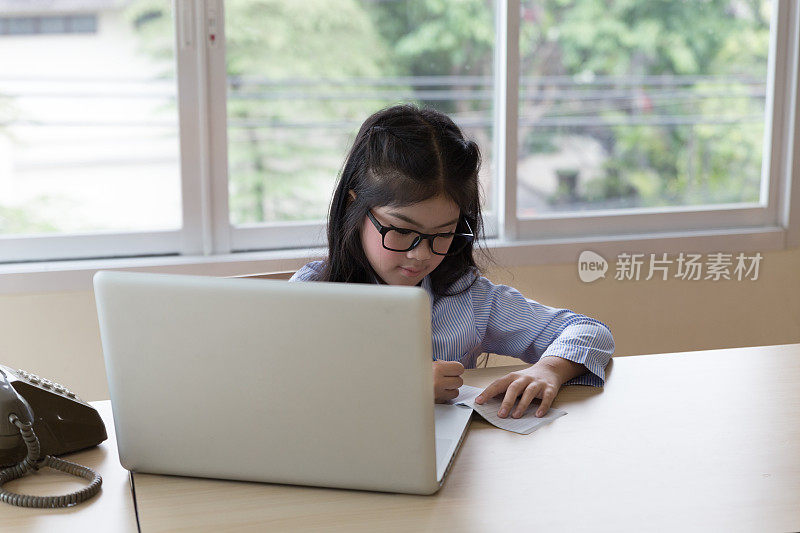 美丽的女学生在网上学习，学习，在家里的书桌上写笔记
