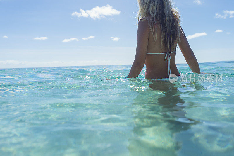 妇女涉水在热带海滩碧绿的水。
