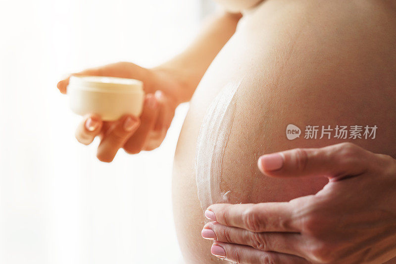 孕妇在腹部涂抹乳霜以防止皮肤上的妊娠纹