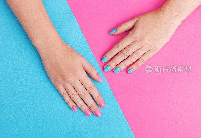 一个年轻女子的手的特写与指甲上的粉红色背景
