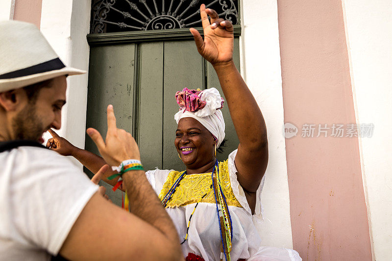 在巴西巴伊亚州萨尔瓦多的Pelourinho，游客与“Baiana”女子跳舞