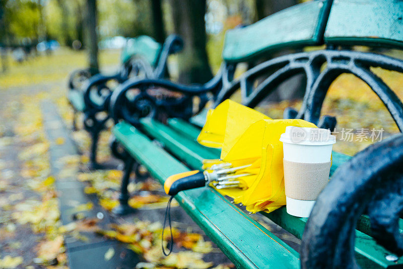 公园里的长椅，带着雨伞和一杯咖啡