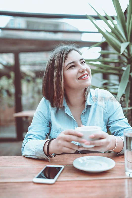 年轻微笑的女性在餐厅享受咖啡休息时间