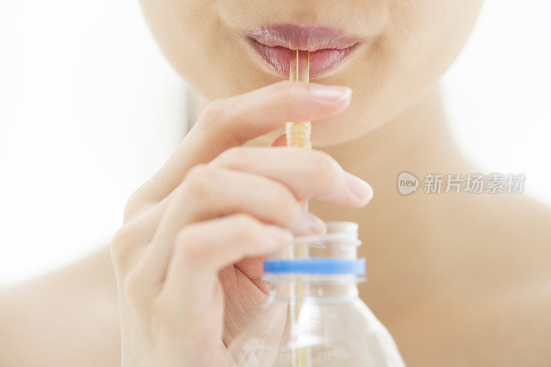 一个女人用吸管吸着塑料瓶里的东西。