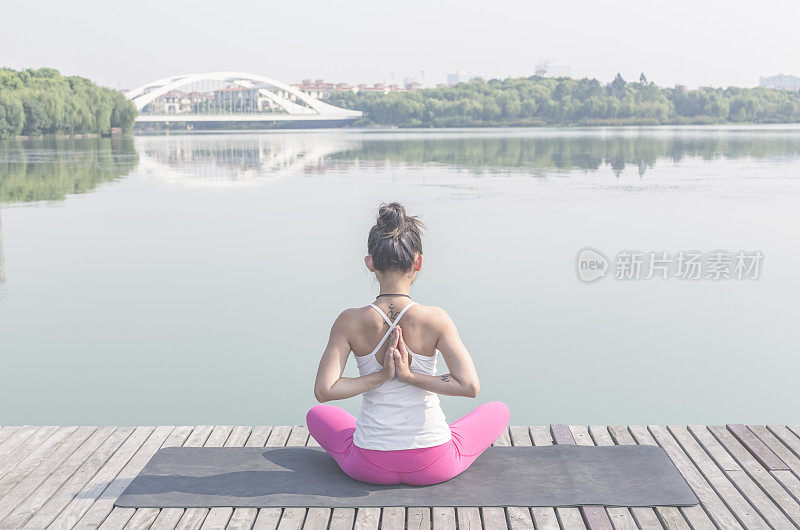 年轻女子在湖边码头做瑜伽