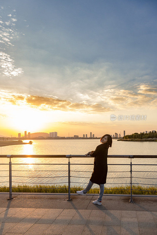 年轻女子在公园人行桥上欣赏美丽的日落风景