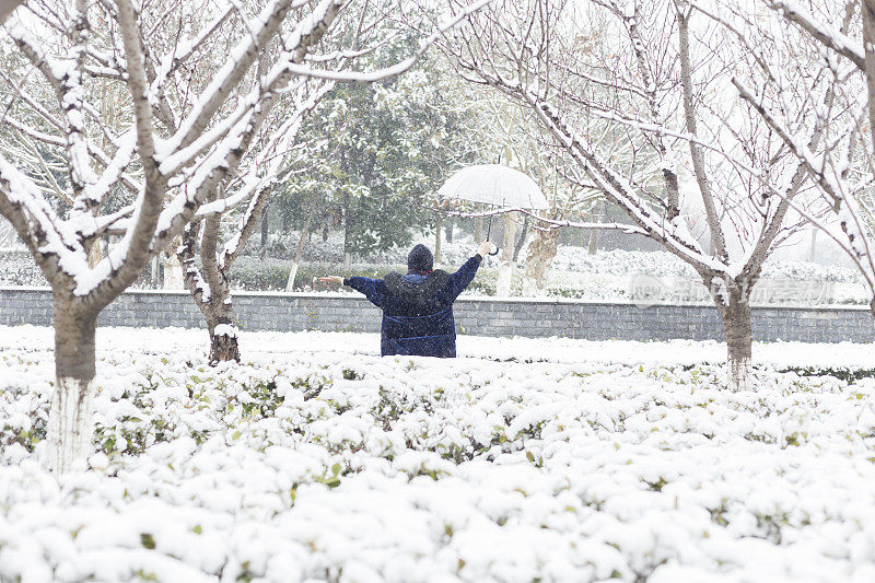 年轻孕妇在公园里享受降雪