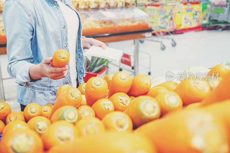 亚洲女性在超市购买胡萝卜和健康食品蔬菜