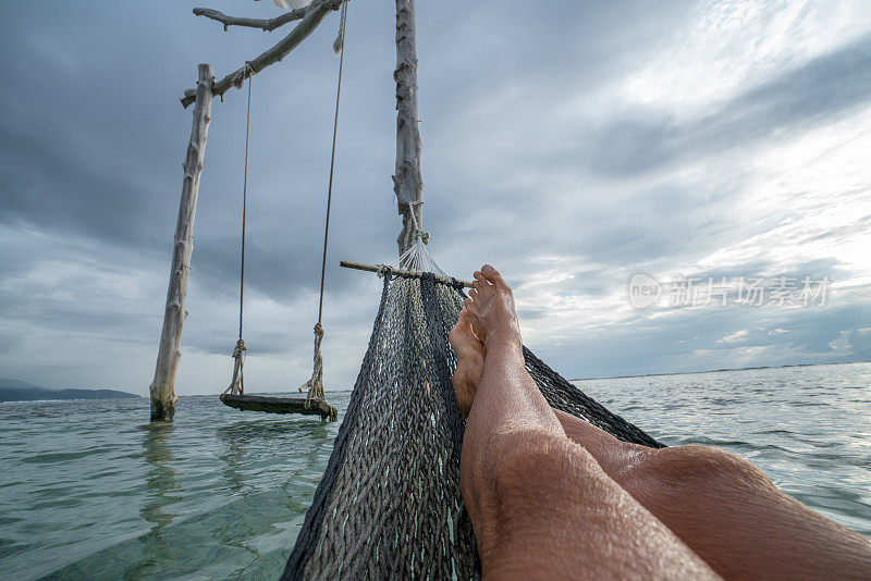 个人视角的人放松在吊床上的海上，脚的观点-
