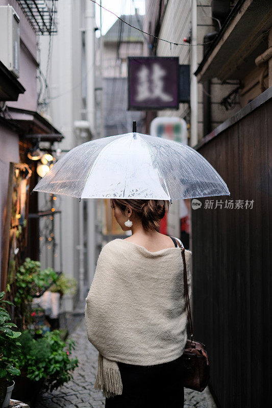 在一个雨天，在东京神乐坂传统老城的小巷里走着的女人的背影