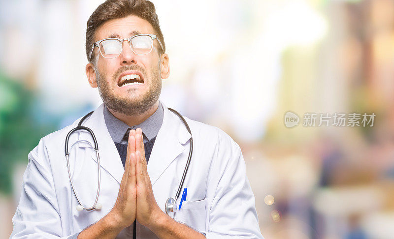 年轻英俊的医生男子在孤立的背景下一起乞讨和祈祷，脸上带着希望的表情非常情绪化和担心。请求宽恕。宗教的概念。