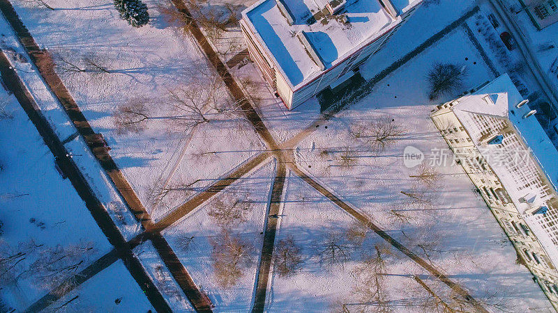 俯视图，正上方鸟瞰被雪覆盖的冬季城市住宅区。复杂的攀爬和旋转摄像机运动