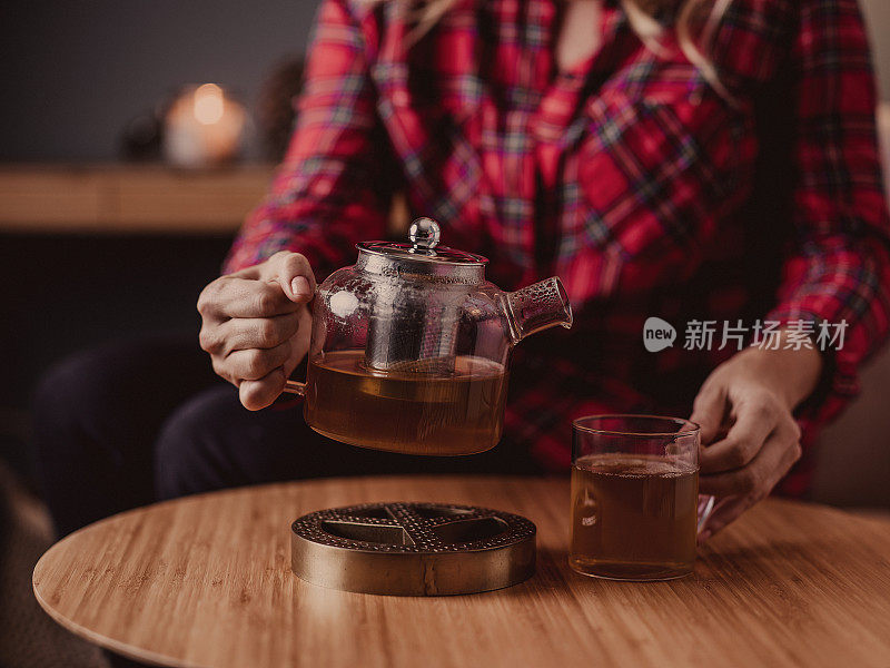 在家里用玻璃茶壶喝茶的女人