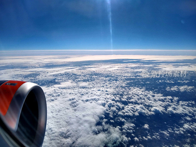 从机舱窗口看，飞机飞在云层之上，捕捉阳光